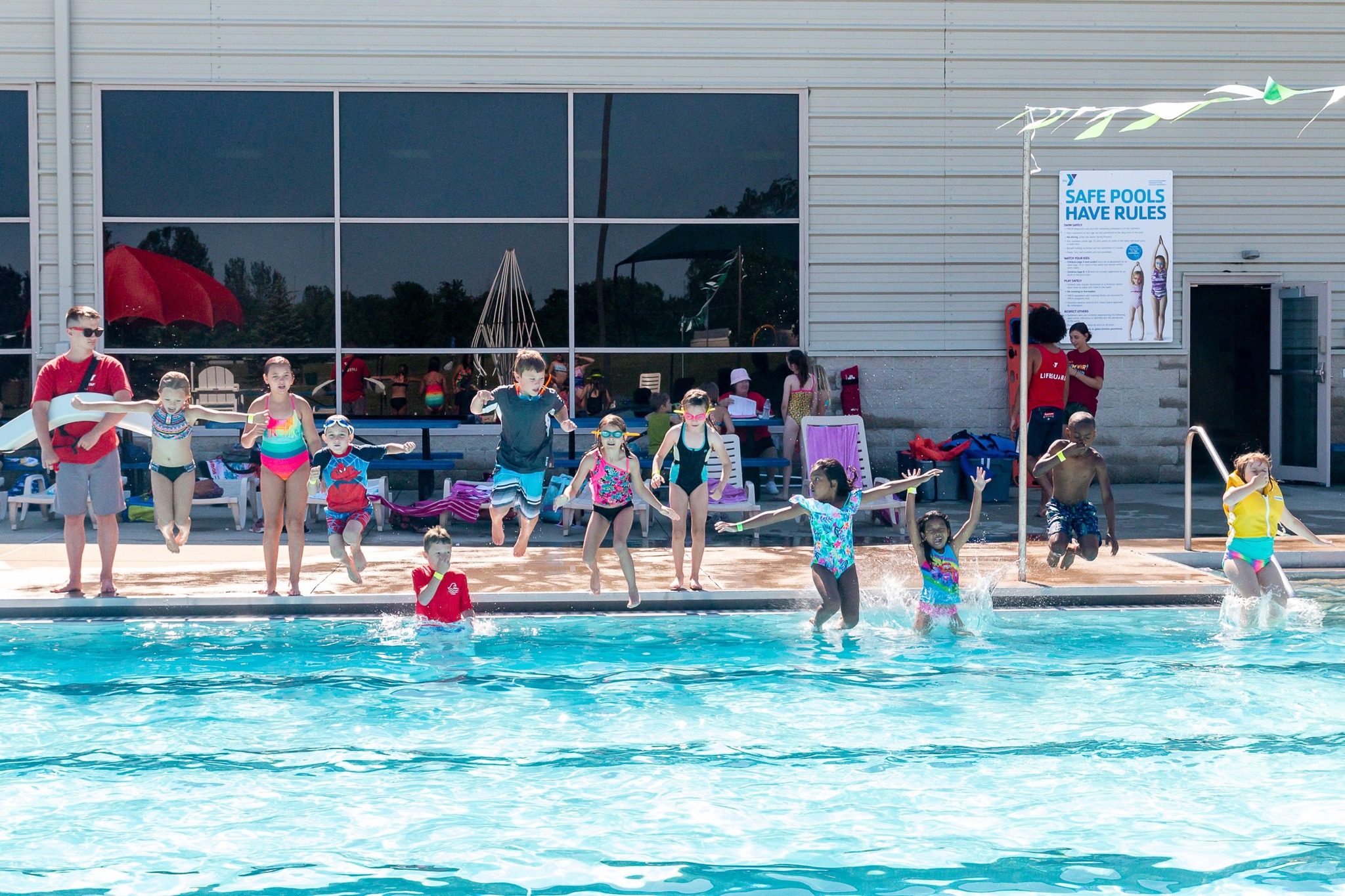 A group of youth jumping into the outdoor pool at the Grove City Pool