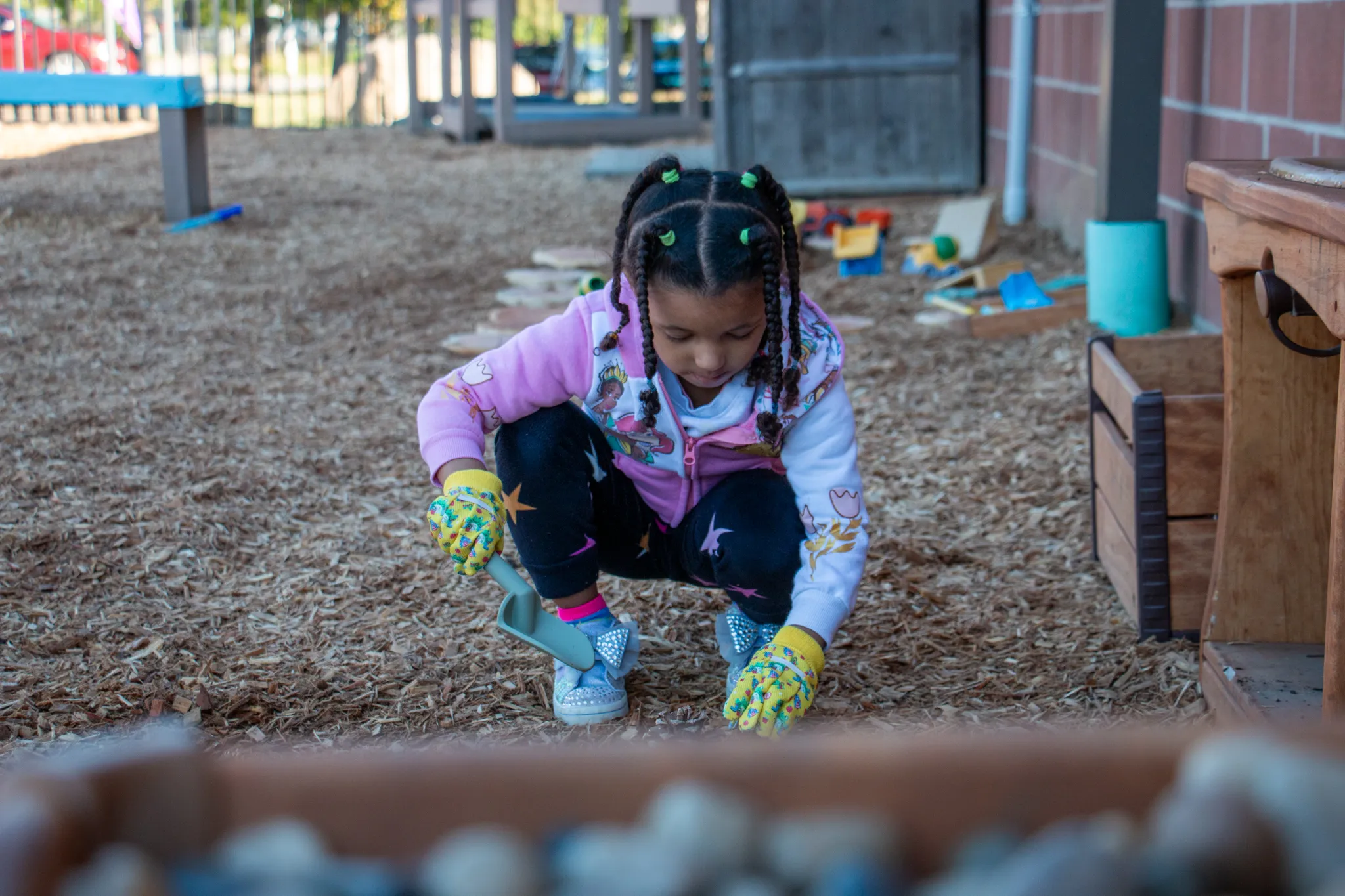 A youth planting seeds in the ground of the Hilltop Playground.