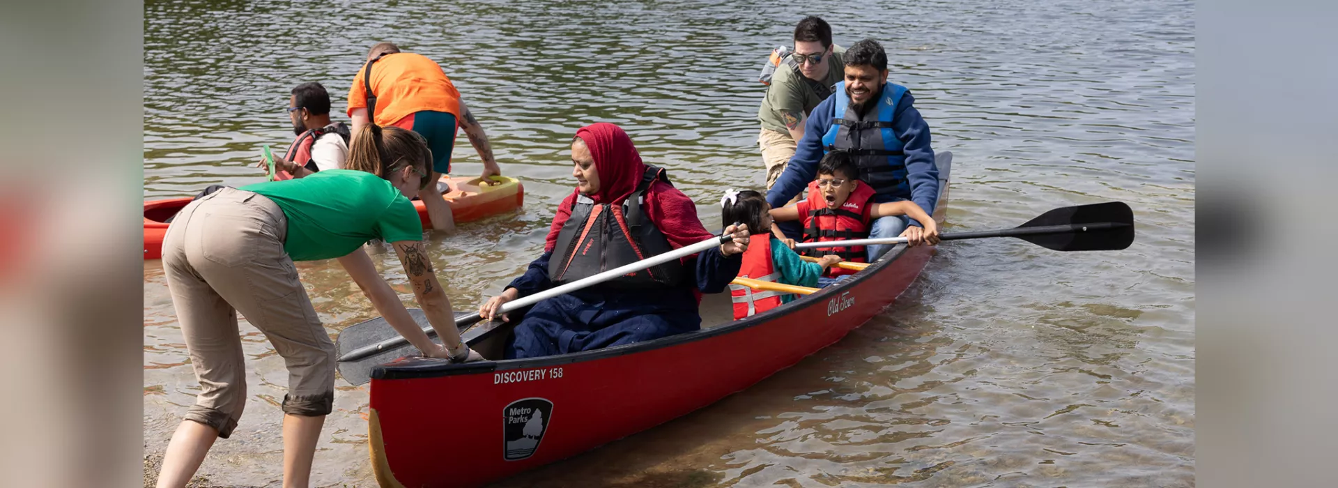 People riding in a canoe with YMCA staff helping them