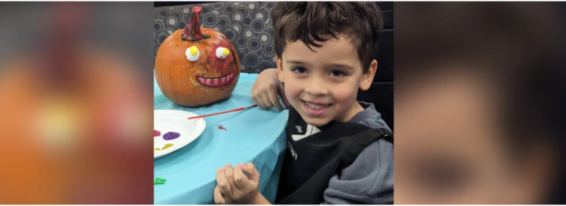 Child with his painted pumpkin siting at a table