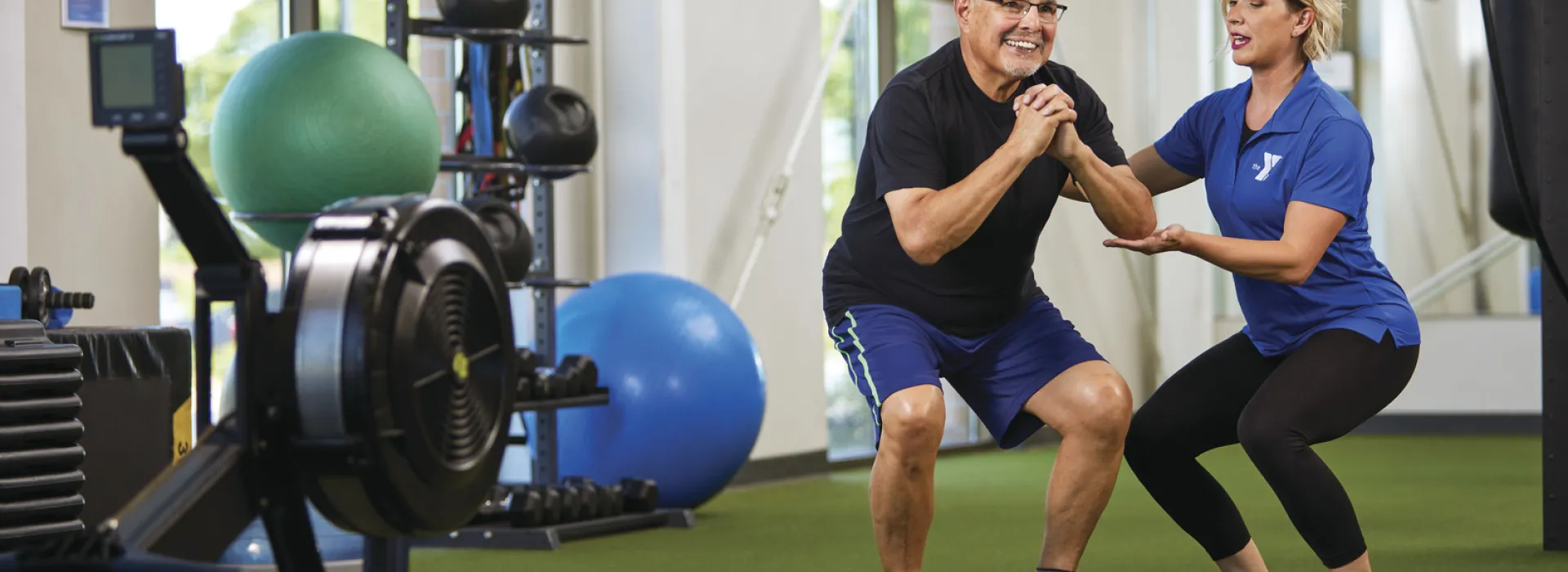 A YMCA trainer helping out a YMCA member with their exercises.
