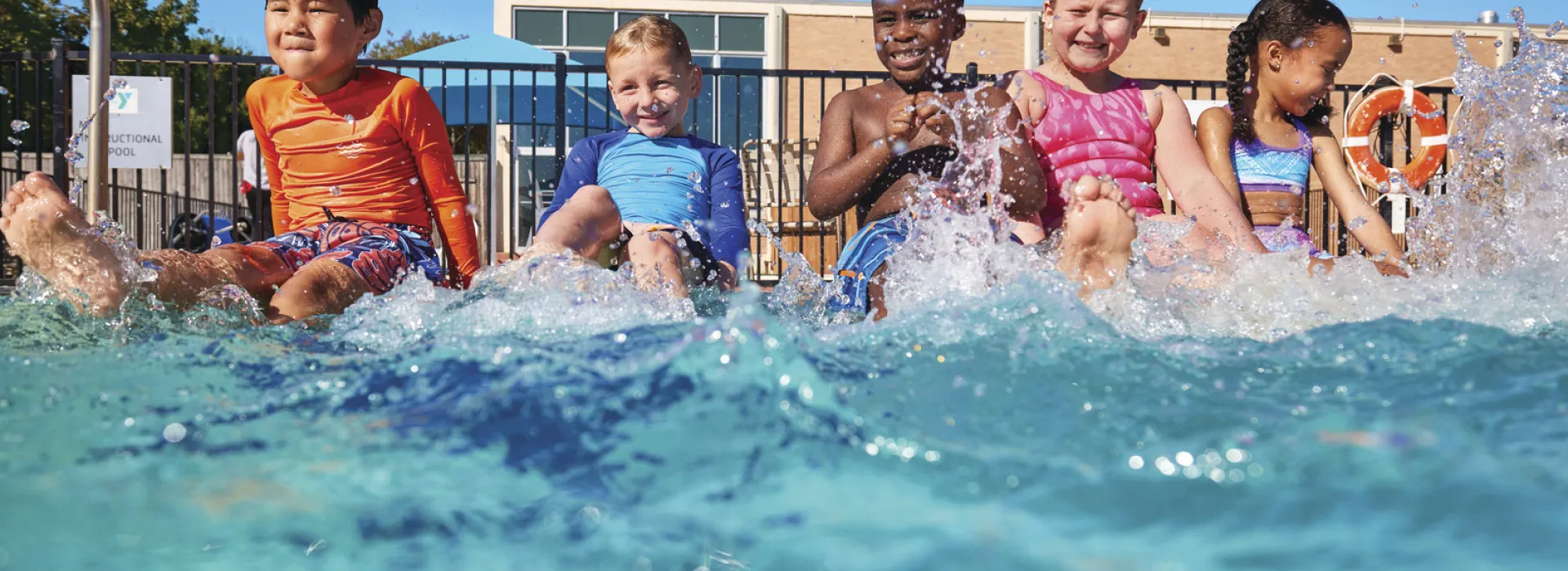 A group of youth enjoying the pool water and splashing about