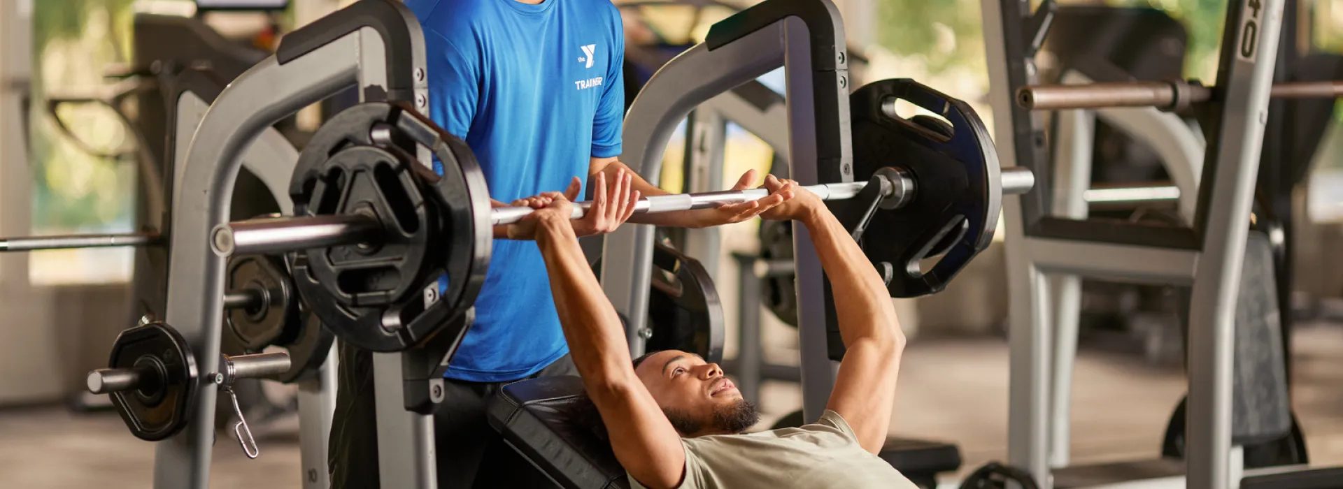 A YMCA trainer helping out a YMCA member with their exercises.