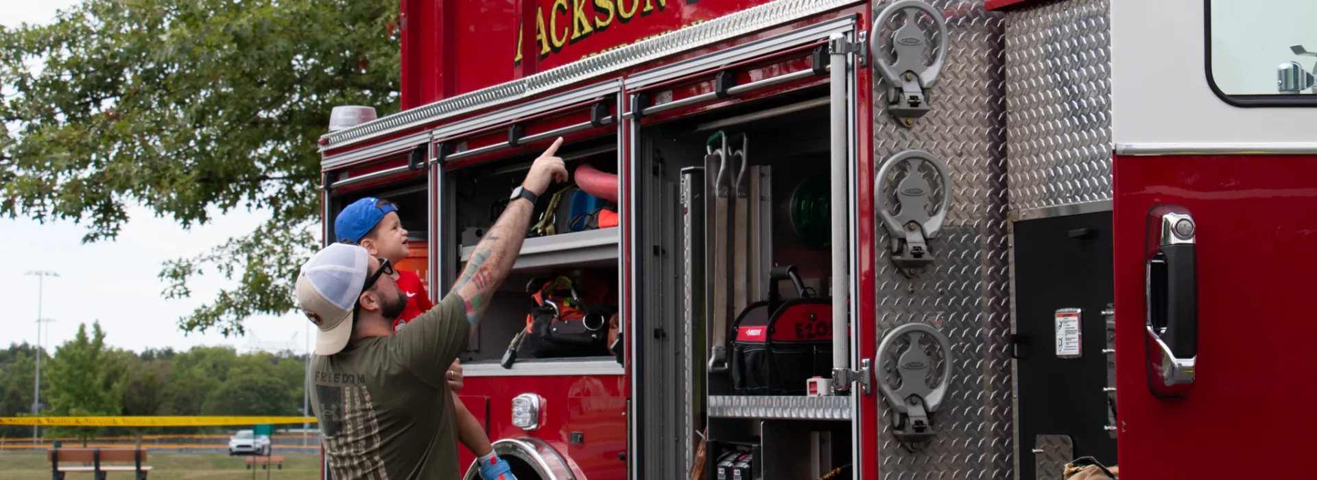 Grove City Family Fun man holding his youth up to a firetruck
